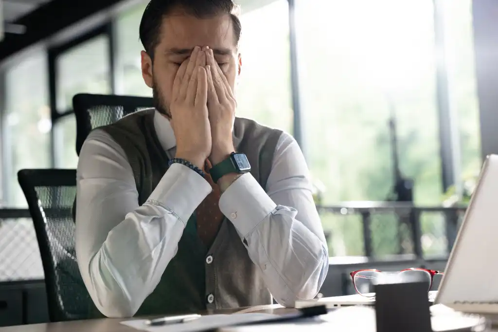 Feeling exhausted. Frustrated middle-aged beard man massaging his nose and keeping eyes closed while sitting at his working place in office