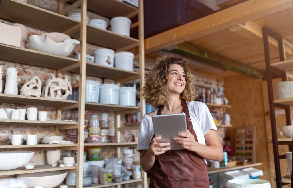 photo of woman in pottery studio holding a tablet